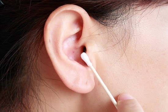 Woman holding a cotton swab up to her ear canal