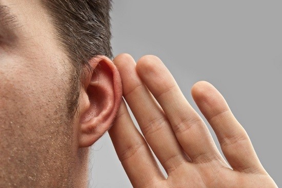 Man holding hand to ear simulating difficulty hearing