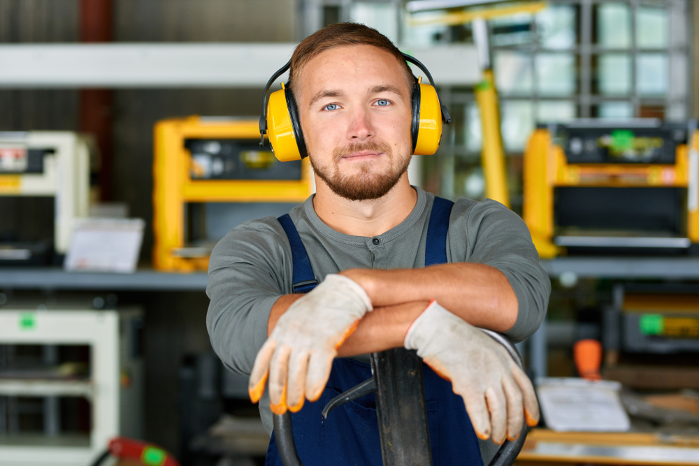 worker wearing protective headphones posing looking at camera.