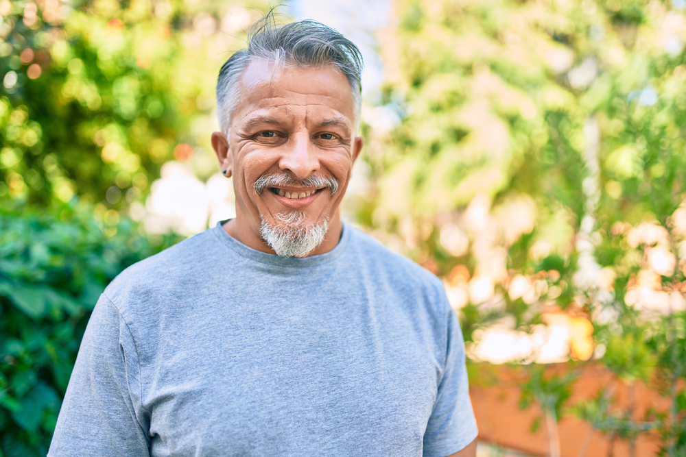 hispanic grey-haired man smiling happy standing at the park.