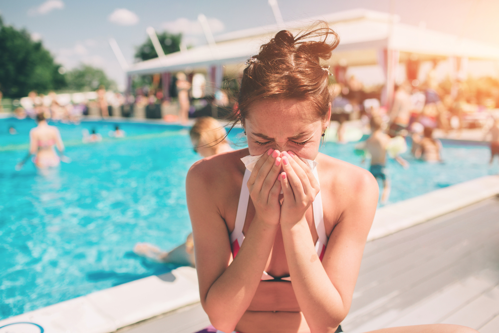 woman sneezing at the pool.