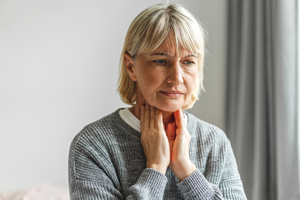 woman touching her neck due to tonsil discomfort.