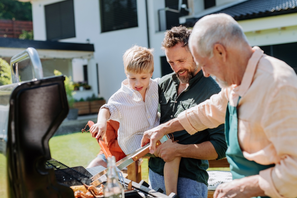 Multi generation family grilling outside on backyard in summer.
