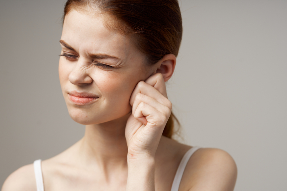 a woman touches her ear and narrowed her eyes.