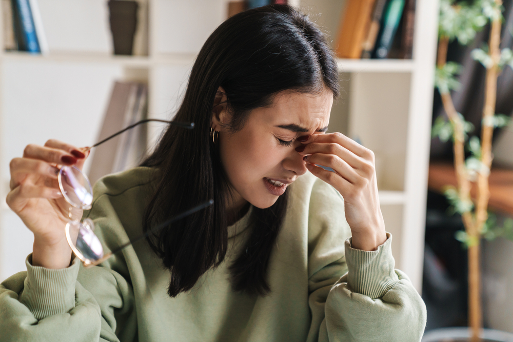 woman touching the bridge of her nose due to pain.