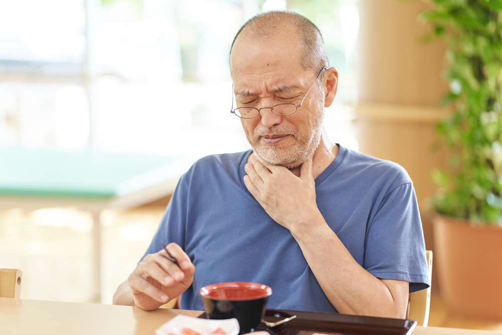 man suffering from trouble swallowing at the table.