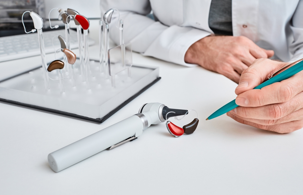 Hearing aid specialist reviewing hearing aid options at a table.