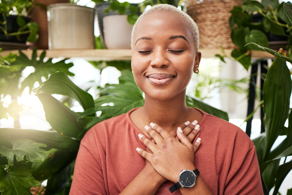 woman practicing meditation next to plants.