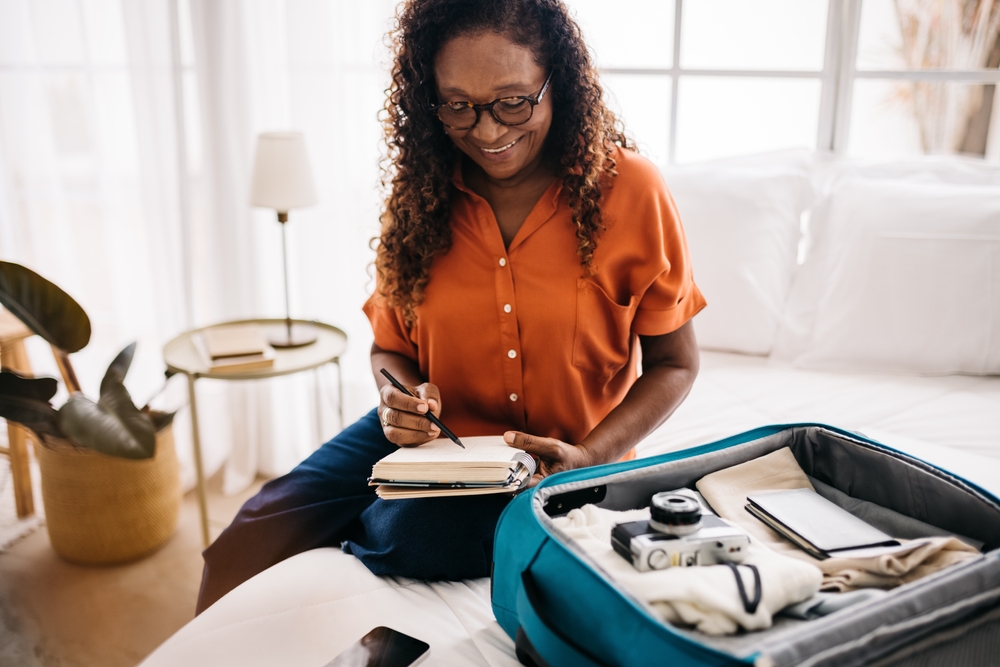 woman planning a vacation with a checklist list, packing things into her luggage.