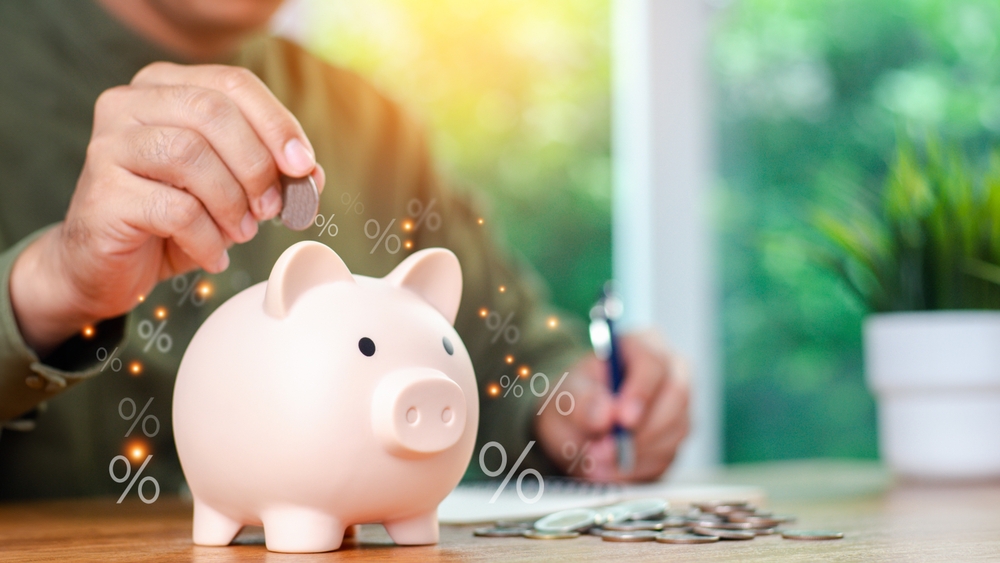 Concepts of saving money and financial planning. Man hand holding piggy bank on wood table.