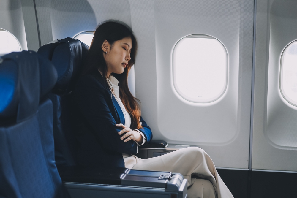 Asian woman sitting in a seat in airplane.