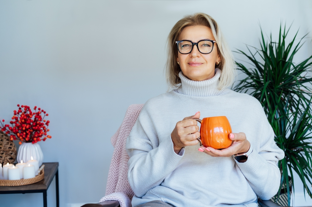 woman relaxing with pumpkin shaped cup of hot drink.