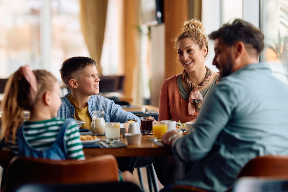 Happy family communicating while eating breakfast at dining table.