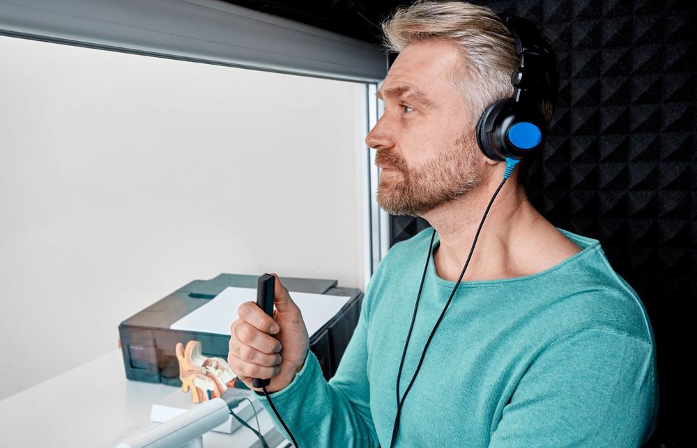 man sitting in audiology booth at hearing clinic.