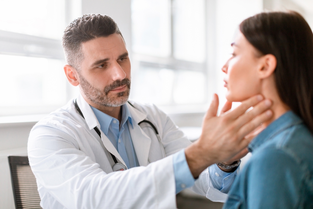 doctor examining throat of young lady in clinic.