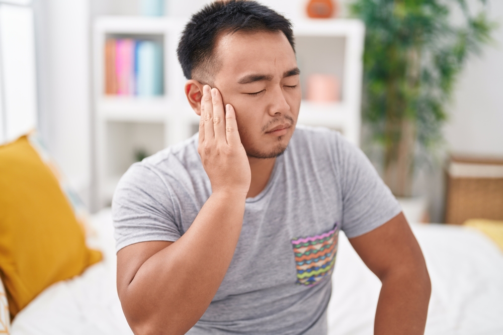 man suffering from ear pain at home.