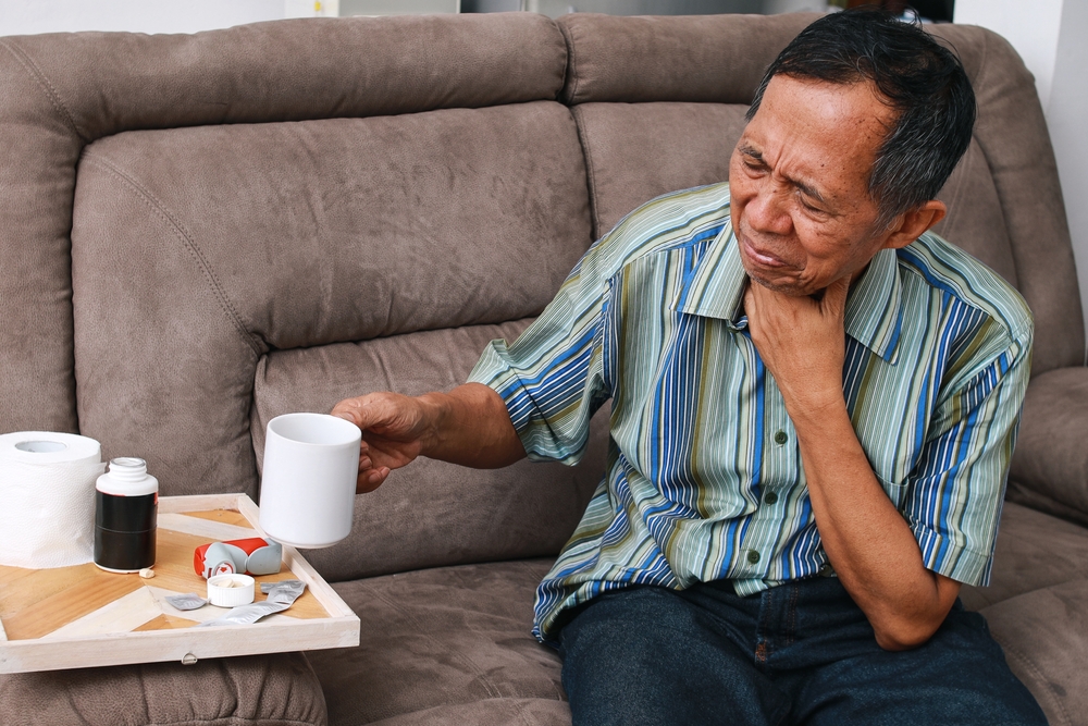 man holding coffee mug, suffering from painful swallowing.