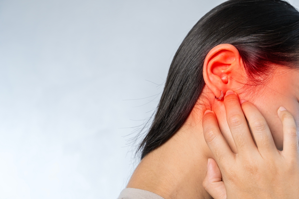 Young woman suffering from ear pain.