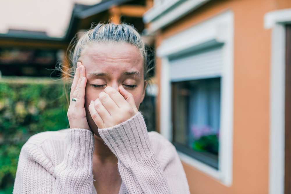 woman touching her nose outside due to sinus infection symptoms.