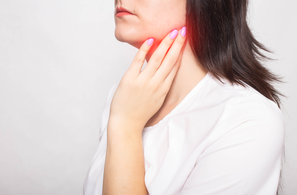 Woman clings to her inflamed salivary gland experiencing pain.