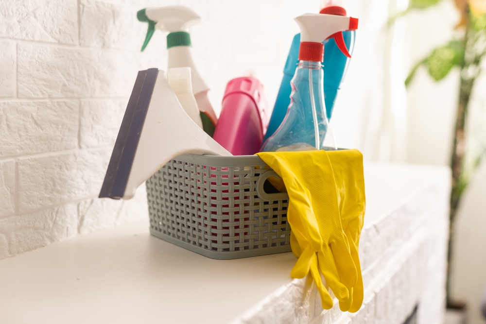 cleaning and household products in grey storage bin on white counter.