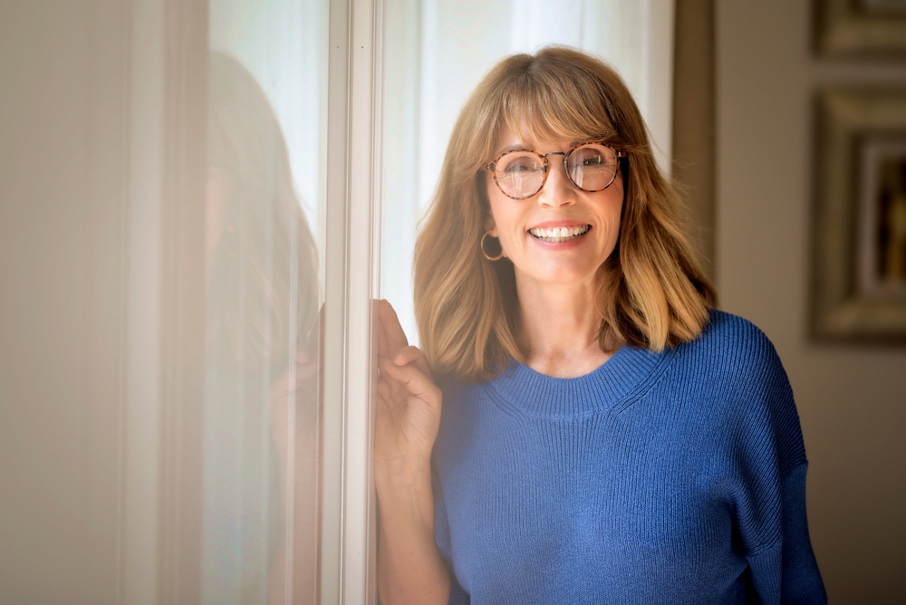 Blond haired female wearing blue shirt and eyewear.