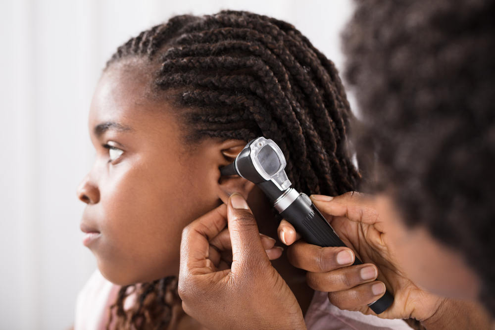 doctor looking into child's ear with an otoscope.