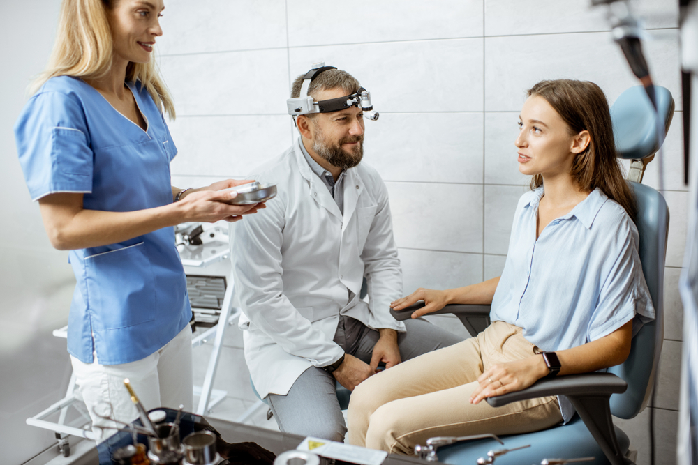 otolaryngologist and female assistant in ENT office during a medical examination.