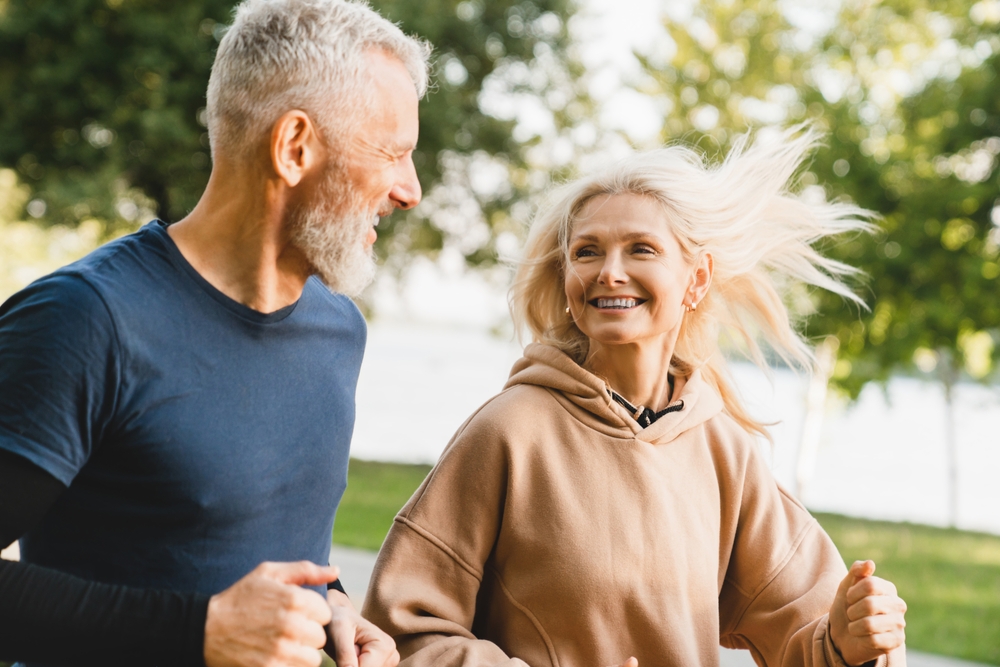 couple running together in the park looking at each other while jogging.