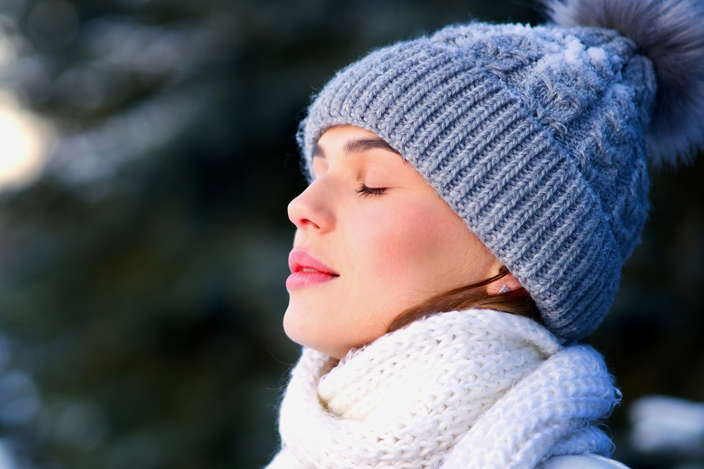 young woman is breathing deep deeply fresh air during winter.