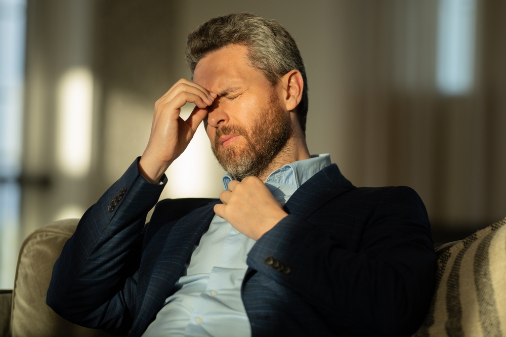 man touching between eyes due to a sinus headache.