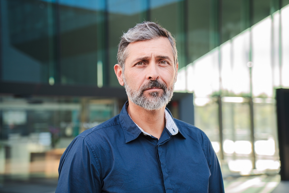 A middle-aged male wearing a shirt staring front thoughtfully.