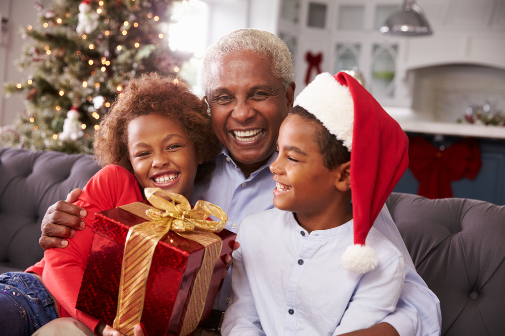 Grandfather With Grandchildren Opening Christmas Gifts.