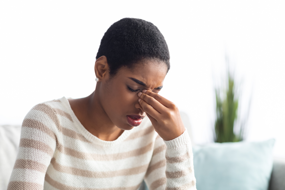 woman touching the bridge of her nose due to sinus pressure and symptoms.