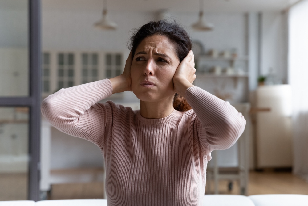 woman covering up her ears due to tinnitus noise.