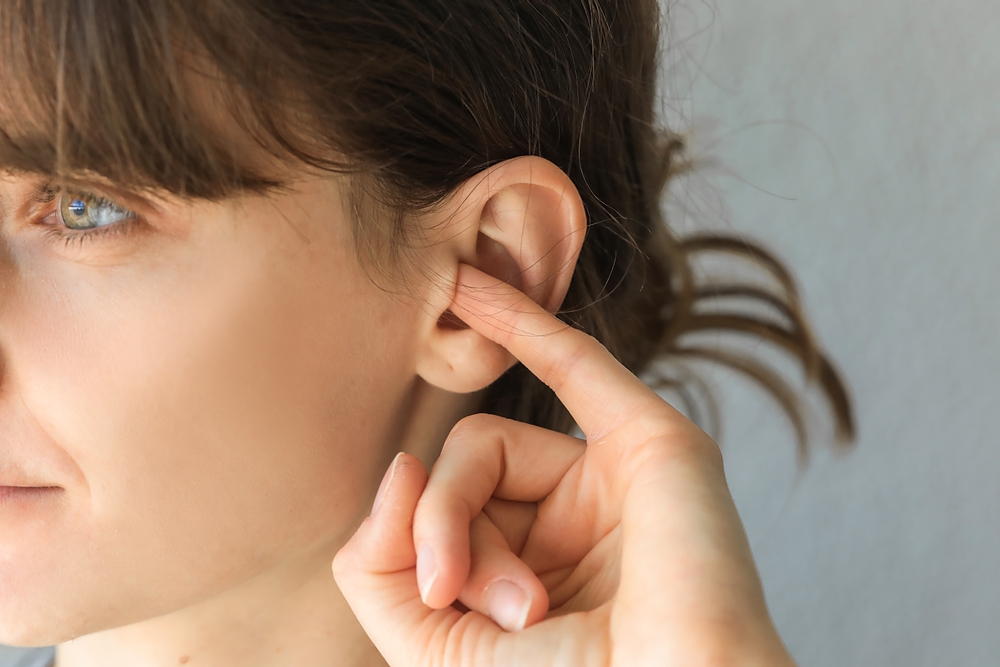 woman putting finger in ear.