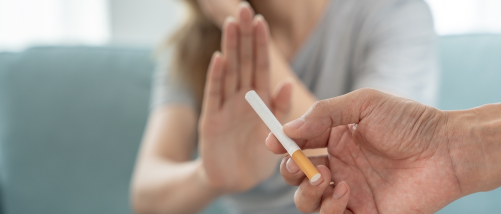 Woman pushes hand away from person handing her cigarette.