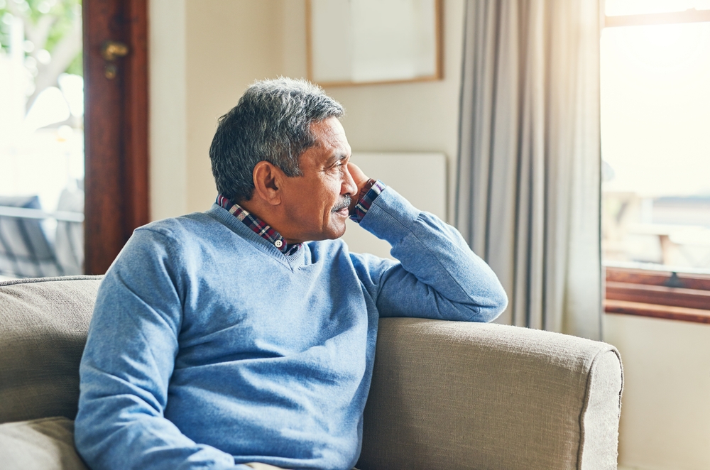 lonely man sitting in living room looking out the window.