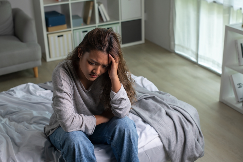 woman sitting in bedroom suffering from depression.