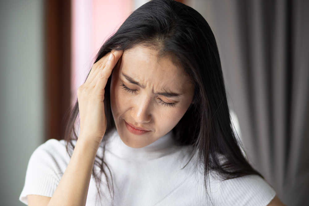 woman holding head due to tinnitus symptoms.