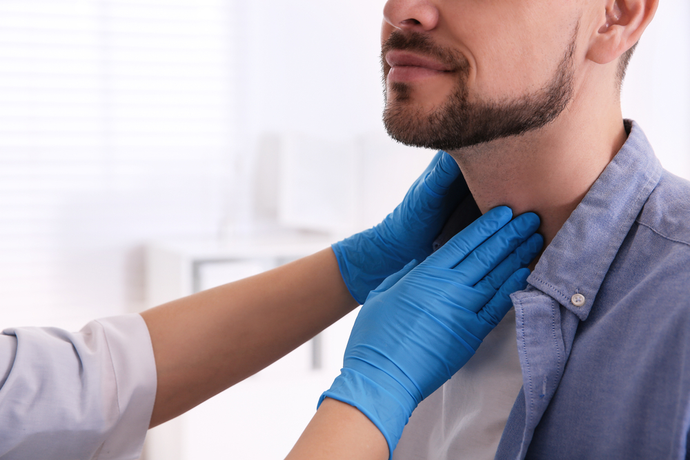 Doctor examining thyroid gland of patient.