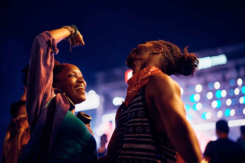 man and woman dancing during an outdoor concert.